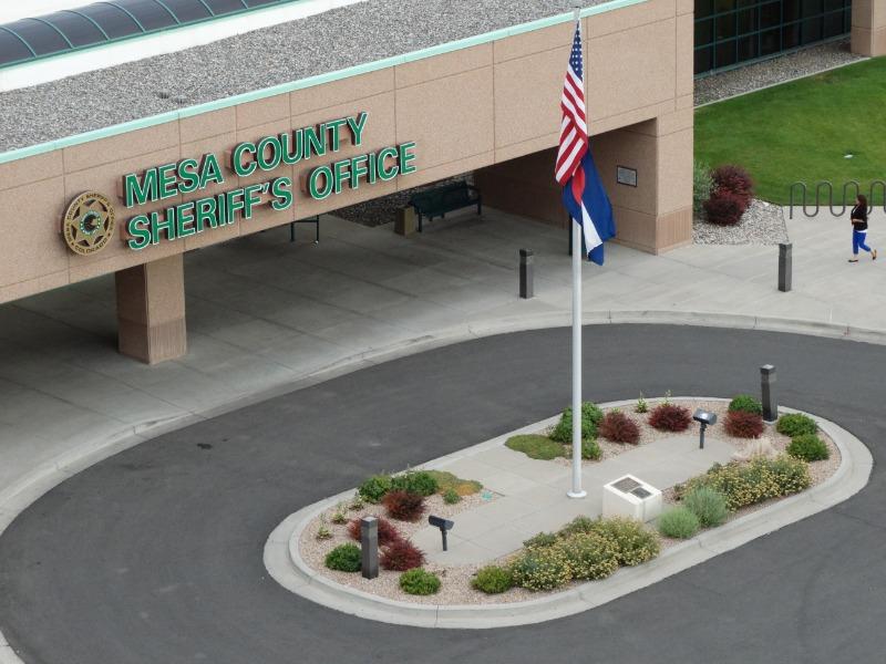 Outside of Mesa County Sheriff's Office building showing driveway and flagpole with U.S. and State of Colorado flags.