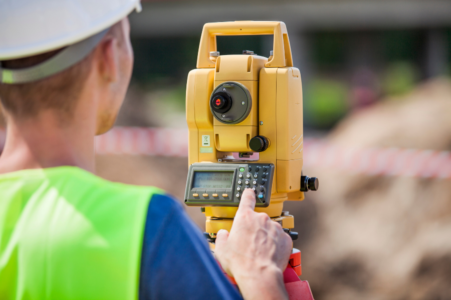 A man uses a theodolite to survey land 