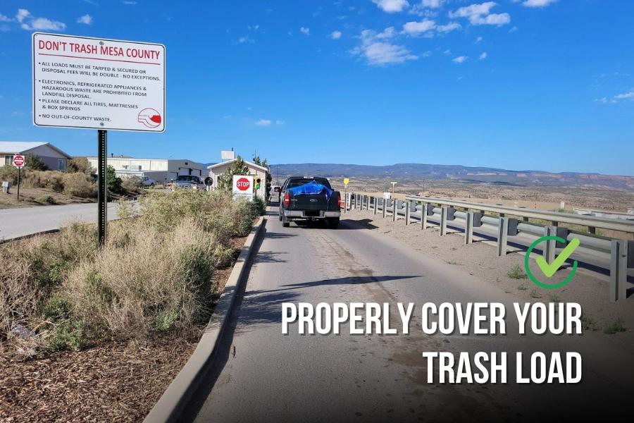 Black truck driving into Mesa County Landfill on clear day with sign reading, 'don't trash Mesa County," 