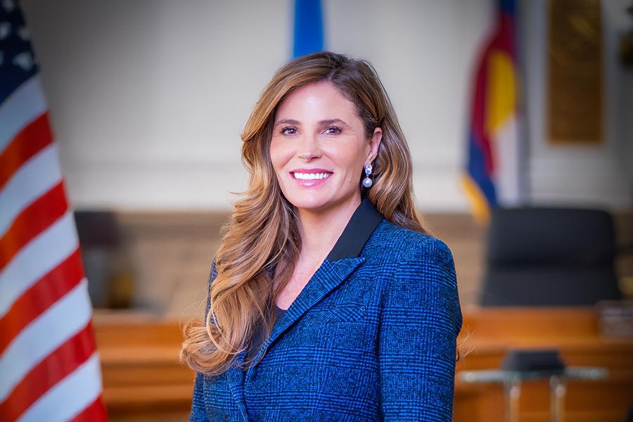 Woman (Mesa County Commissioner Bobbie Daniel) smiling for headshot in front of American flag. 