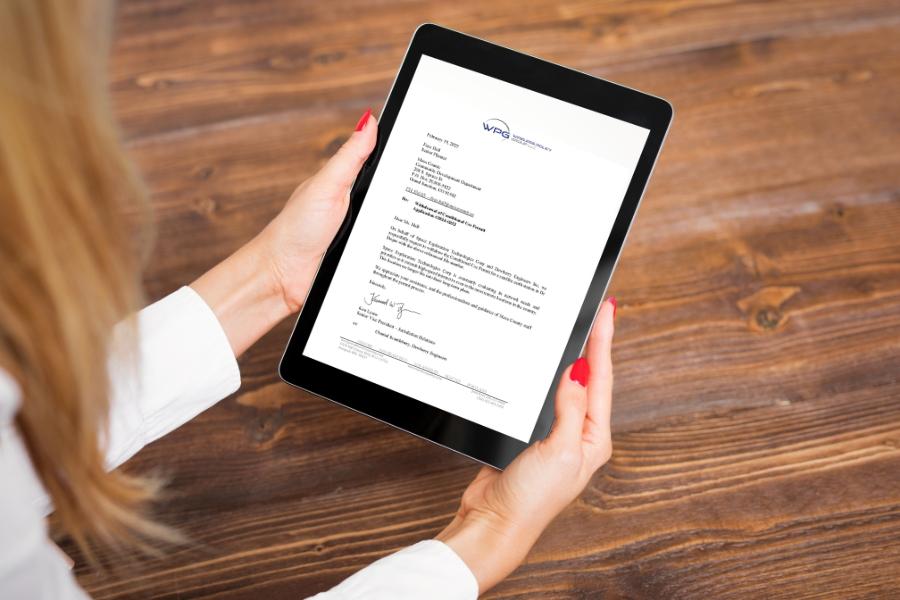 Hands holding an iPad displaying a letter. 