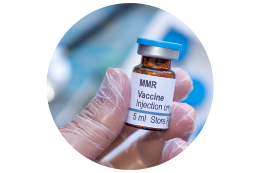 A gloved hand holding a small vile of MMR vaccine.
