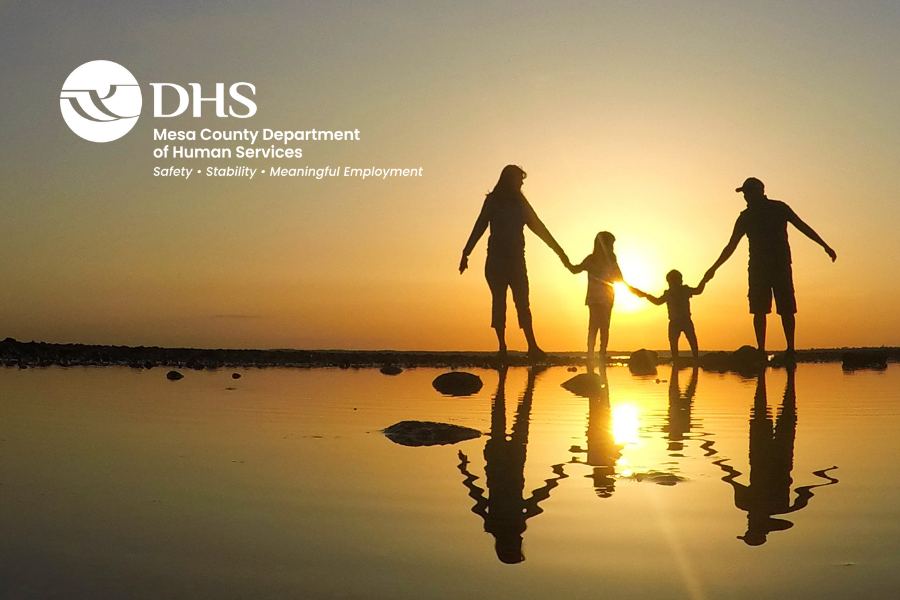 Family walking on the beach at sunset with DHS logo.