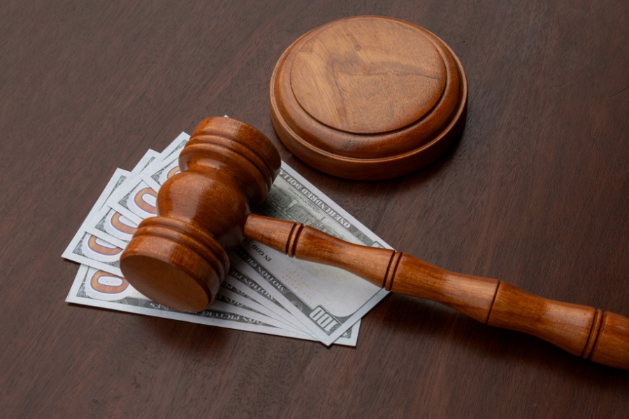 Gavel resting atop a pile of cash on a desk