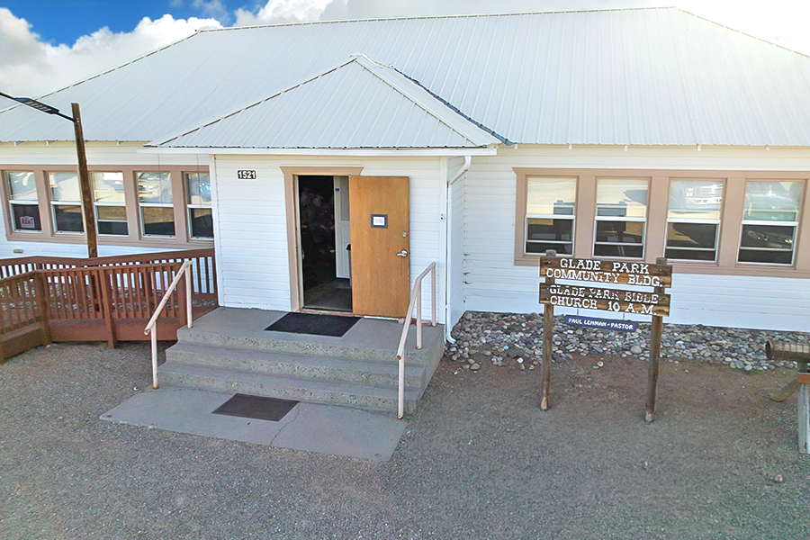 Exterior view of the Glade Park Community Building, a white building with a metal roof, front steps, an accessibility ramp and a sign identifying the facility.